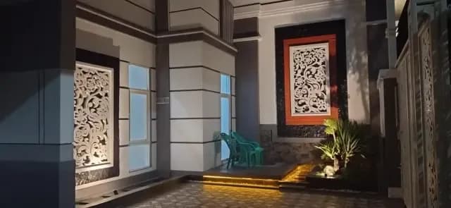 Dinding eksterior dengan panel ukir dan lampu taman
