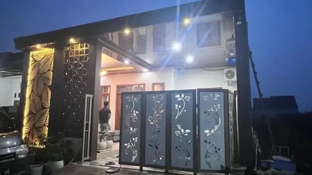 Fasad rumah malam hari dengan dinding motif daun bercahaya